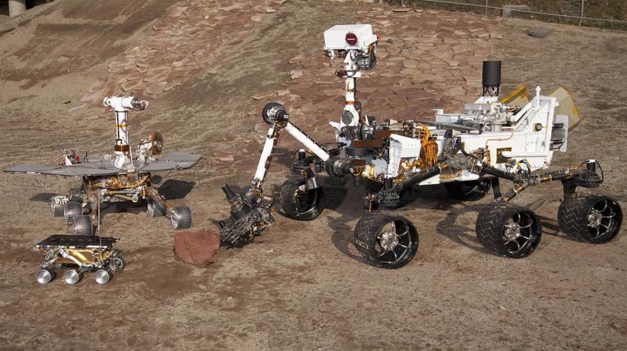 Three rovers of varying sizes are seen on Mars.