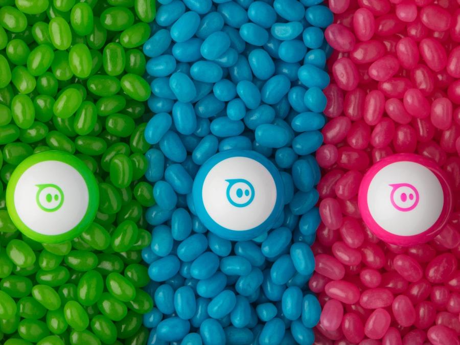 Three piles of colorful jellybeans, each with a color matching Sphero mini on top, in green, blue, and pink.