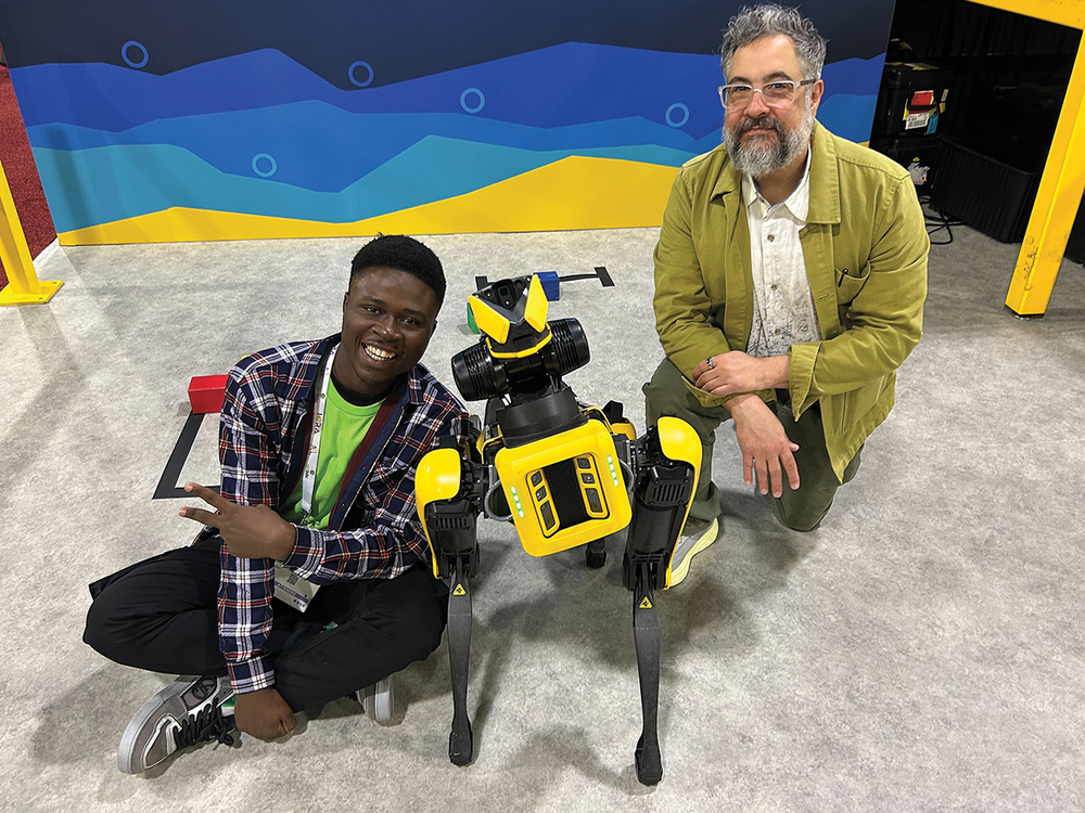 Two people posing with a yellow robot dog at a tech event.